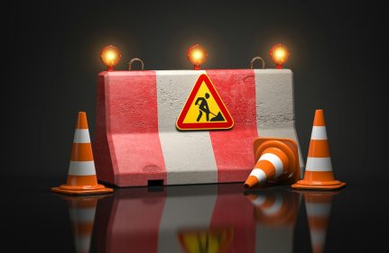 Under construction web site design. Road sign on barrier with traffic cones